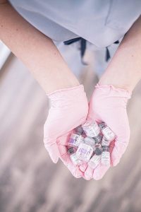 Close-up of hands in pink gloves holding cosmetic treatment vials, symbolizing modern aesthetics.